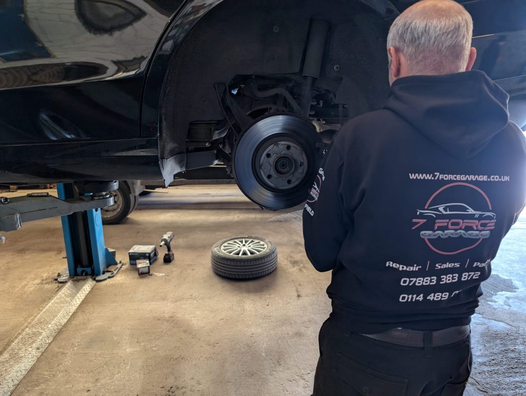 Mechanic inspecting the brakes of a car on a lift at 7 Force Garage Sheffield.